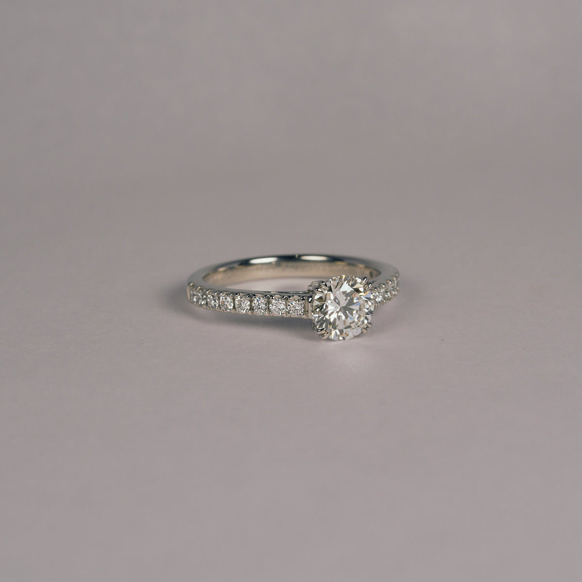 お持ち込みのダイヤモンドをハーフエタニティのアームに留めた、プラチナ950の婚約指輪